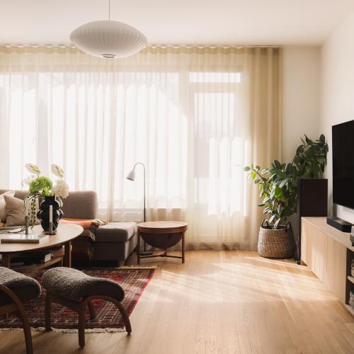 Stue med eikeinnredning for TV, vinyl og musikksamling samt store vindusflater.